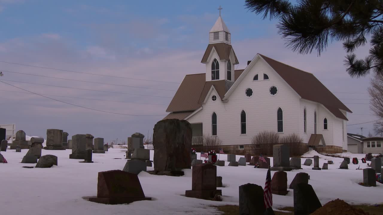 전경에 눈과 무덤이 있는 흰색 교회