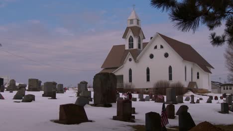 a white church with snow and graves in foreground