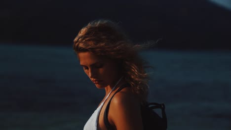 a young brunette woman is enjoying herself at a tropical beach by sunset. the sun is creating a golden light and her hair is moving in the wind on the perhentian islands in malaysia in slow motion.
