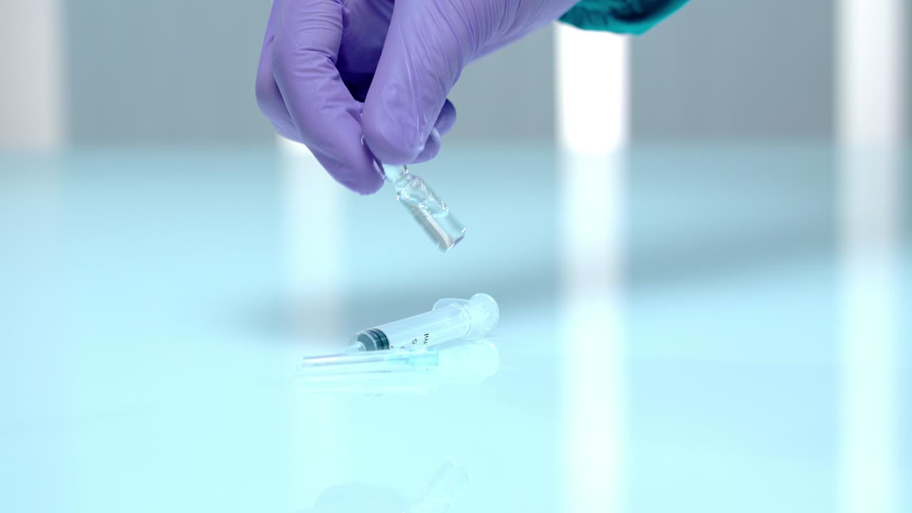 el farmacéutico sostiene el frasco de inyección con la mano. la mano en guantes sacudiendo el vial de medicamento