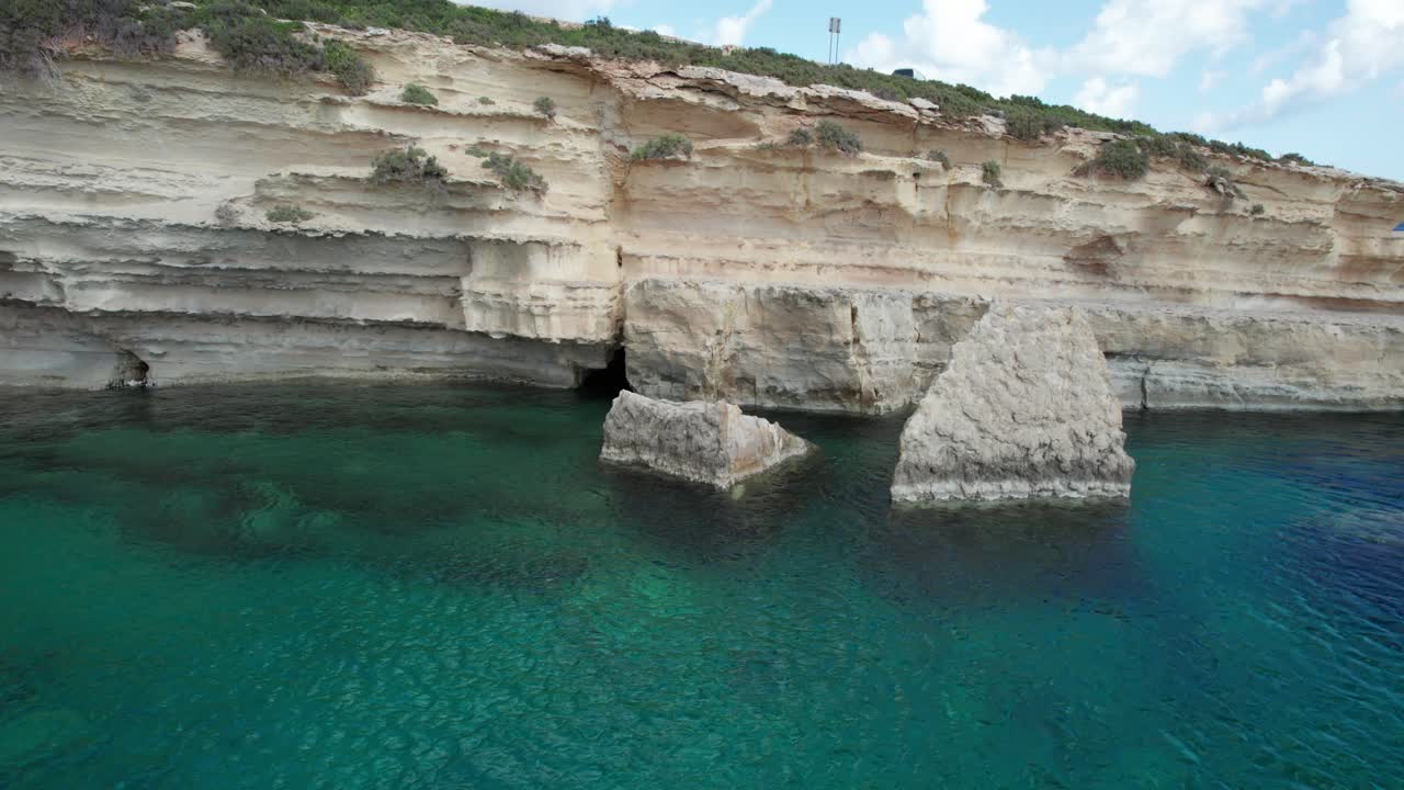 playa de il-kalanka en malta con agua turquesa, salpicando en la pared de piedra caliza