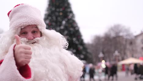 Santa Claus Shows Thumb up Man Looks at Camera and Smiles Focusing on Hand with Gesture Santa Claus Shows Thumb up Man Looks at Camera and Smiles Focusing on Hand with Gesture of Sympathy Isolated Christmas Concept