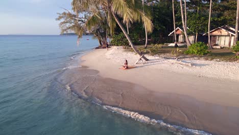 yoga girl sitting on seacret beach under palmtree