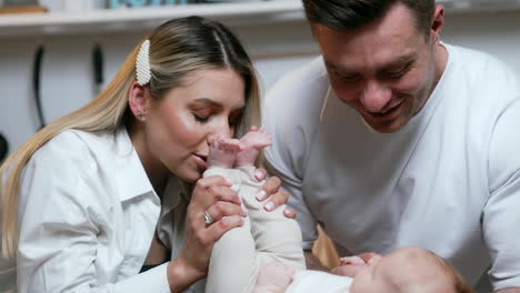caring and loving parents are with their newborn baby. happy mom kisses her child's tiny feet.
