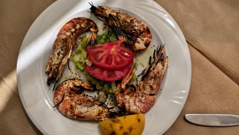gamberetti arrostiti di grandi dimensioni con insalata di pomodoro e lattuga su piatto bianco