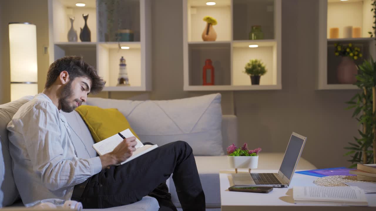 밤에 집에서 일기를 쓰는 행복한 남자. 남자는 생각하고 쓰기도 한다.