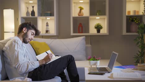 hombre feliz en casa por la noche llevando un diario. hombre que piensa y escribe.