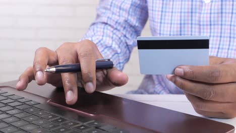 persona que paga con tarjeta de crédito en una computadora portátil