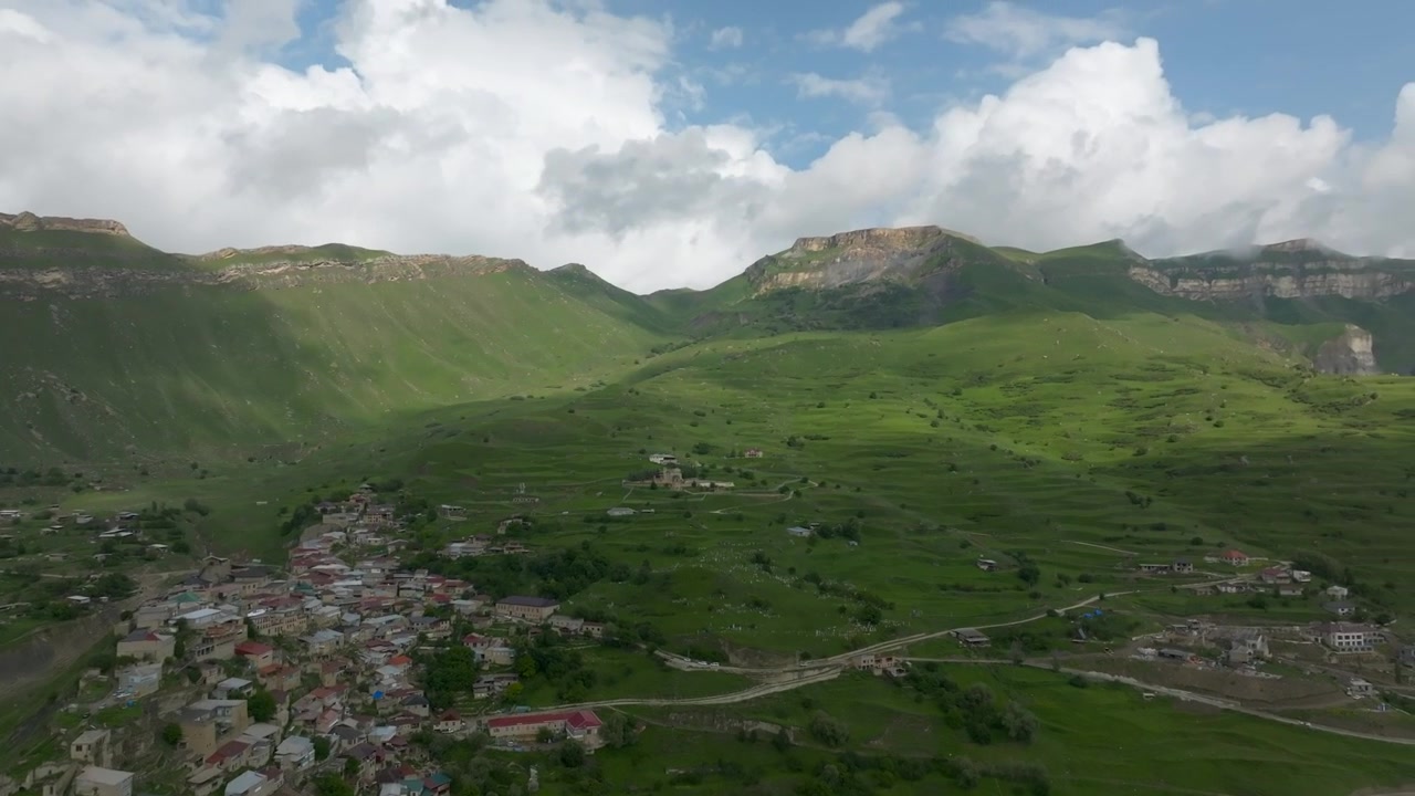 Riprese con drone dell'insediamento rurale di Chokh annidato sui pendii delle montagne con case raggruppate e strade tortuose, circondato da lussureggianti colline verdi nel Daghestan, Russia.