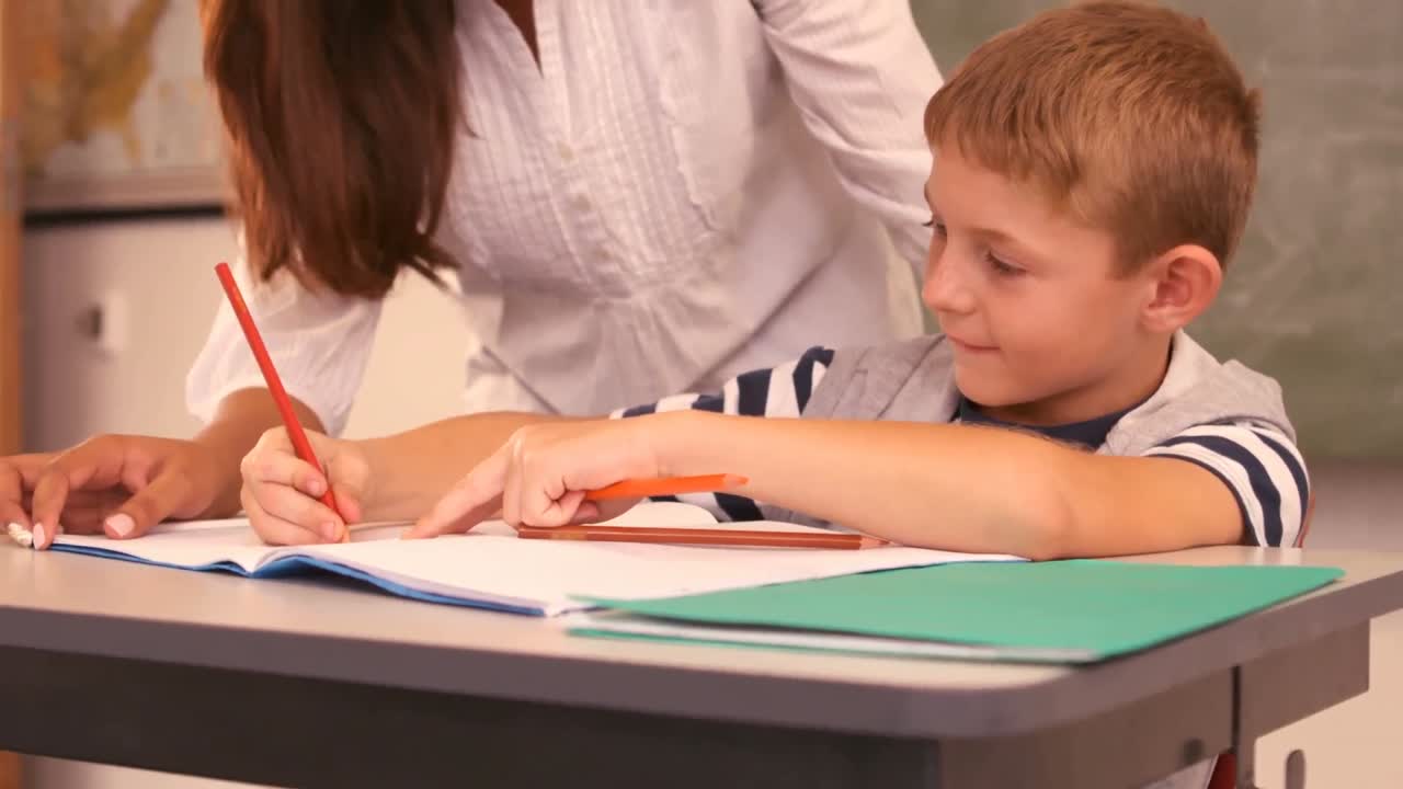 el maestro ayudando a un niño con su tarea en la clase