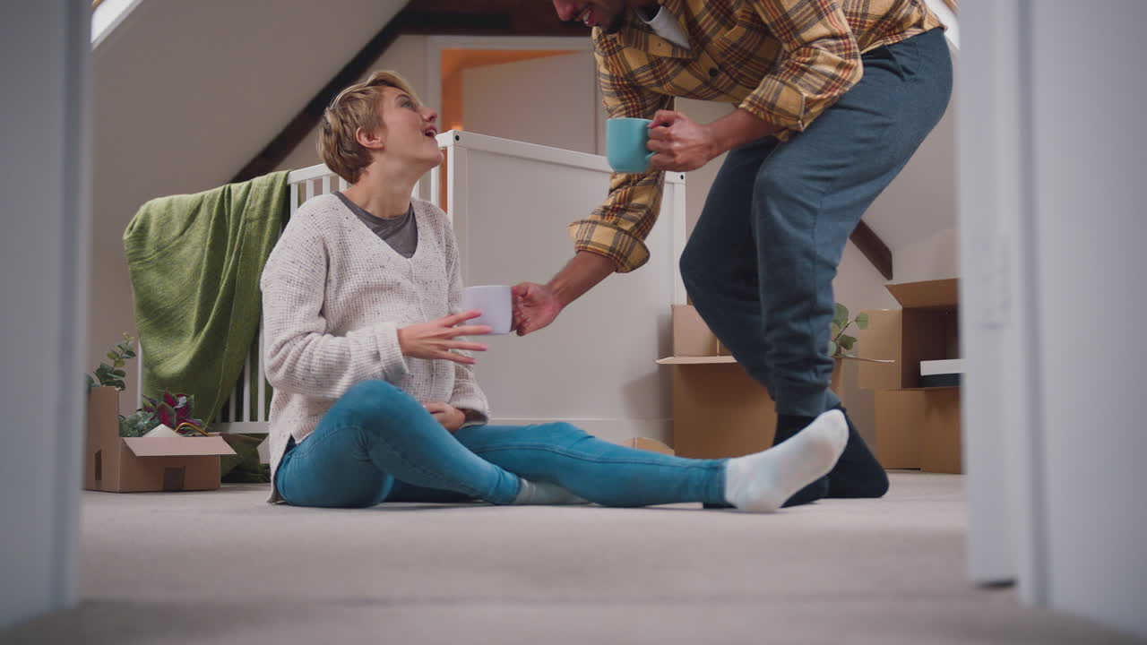 пара ожидает ребенка с горячими напитками в детской комнате нового дома вместе с переездом в коробки
