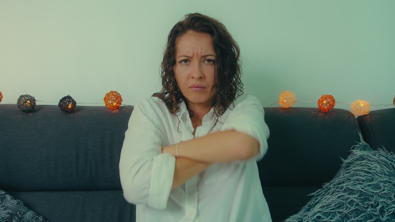 Woman appearing upset or unhappy sitting on a couch