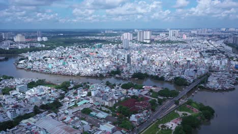 Aerial-view-of-urban-canal,-residential-area-and-urban-sprawl-in-Saigon-or-Ho-Chi-Minh-City,-Vietnam-with-dramatic-sky