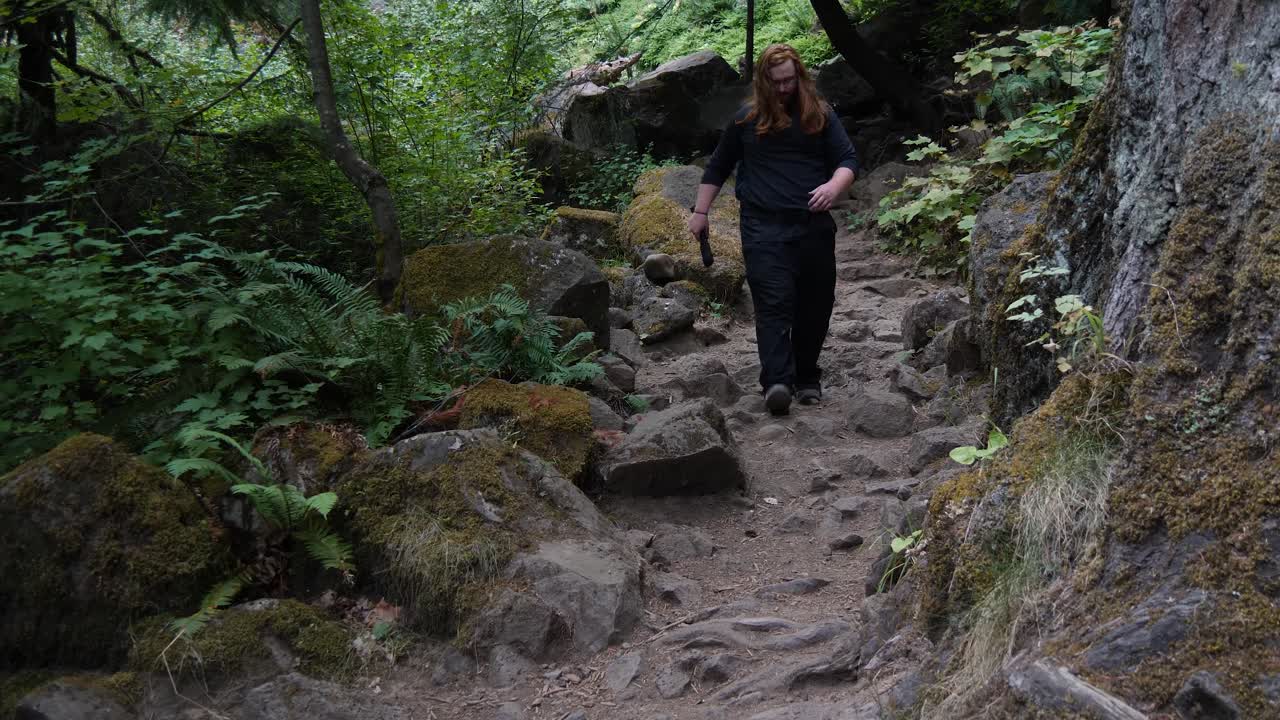 un hombre pelirrojo camina por un sendero cubierto de musgo en oregon