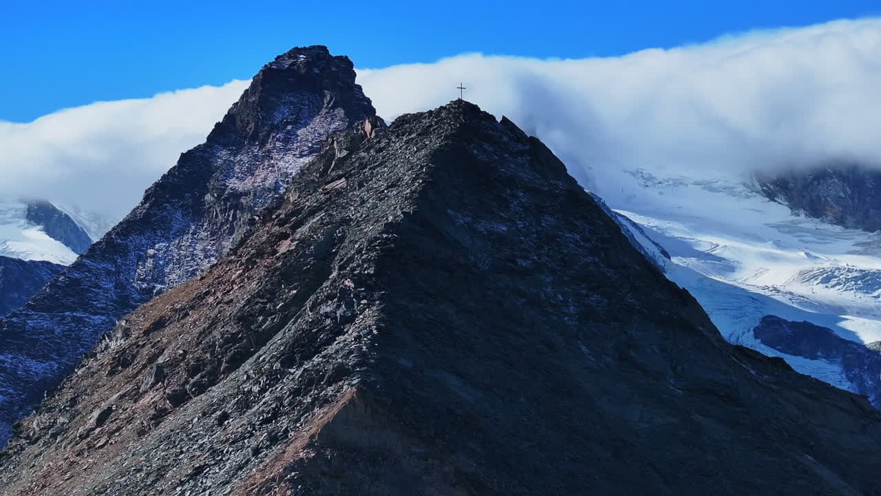 cristiano católico religioso jesús cristo cruzar rocoso glaciar cima de la montaña drone aéreo saas tarifa alpes suizos suiza otoño cielo azul soleado mediodía capa nublada hacia adelante revelar pan up movimiento