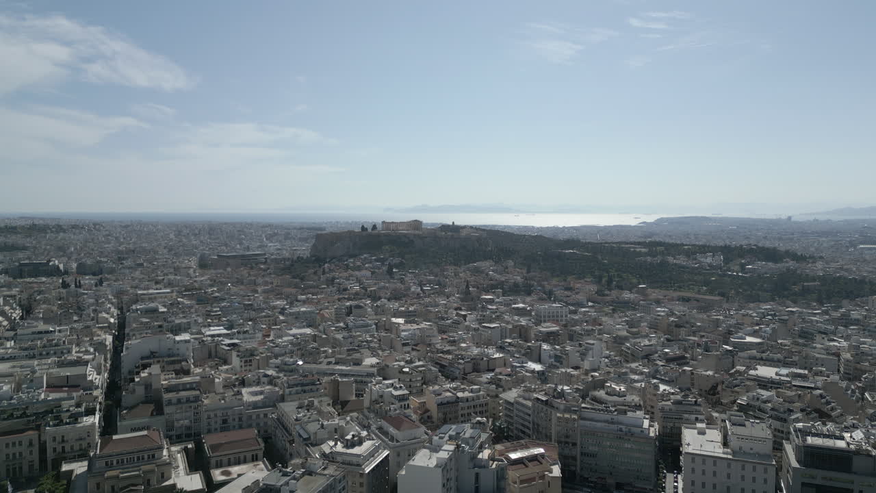 Un drone vola verso il Partenone sopra Atene, mostrando il denso paesaggio urbano e l'iconico Partenone dall'alto