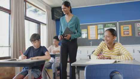 in school, teacher holding tablet while student smiling and listening in classroom
