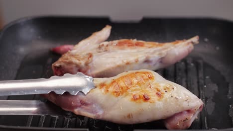 roasted rabbit legs in a grill pan, healthy diet meat close up, chef cooking rabbit on kitchen restaurant, black background. top view