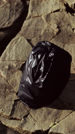 black plastic bag on rocks