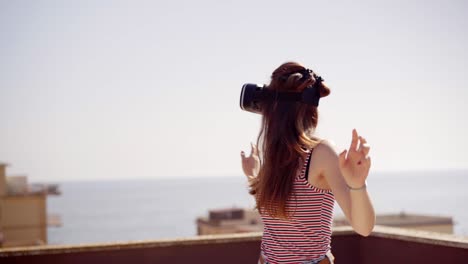 woman uses a virtual reality glasses on the roof. female wearing futuristic vr box headset