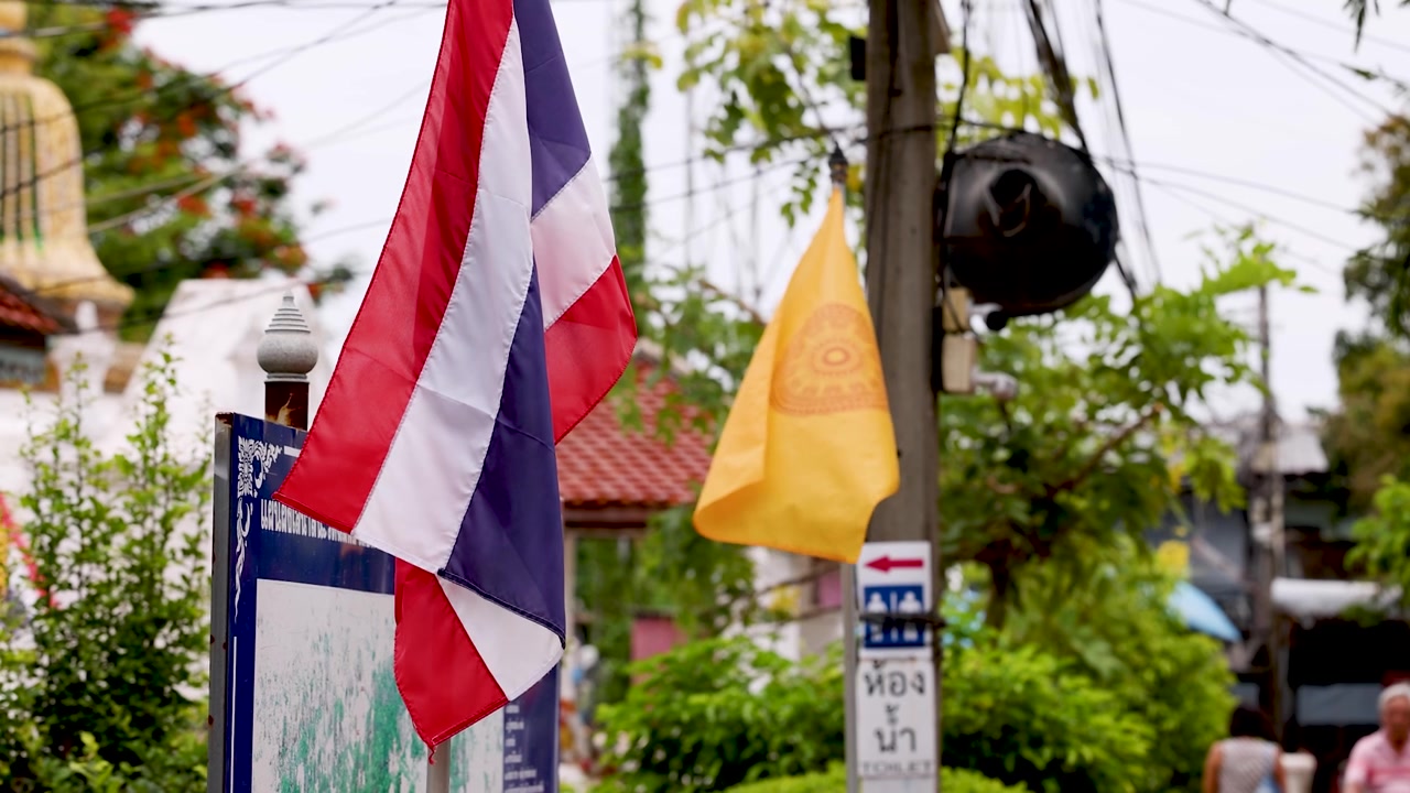 Static medium shot of national and religious flags fluttering outdoors near a traditional temple.
