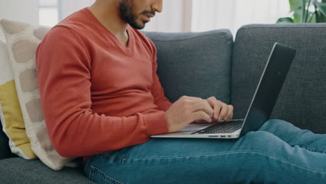 man frustrated on sofa thinking with laptop