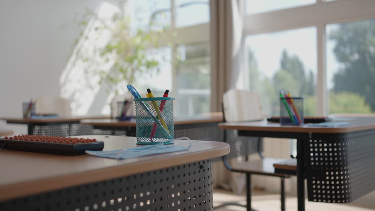 비어있는 어두운 교실에 떨어지는 빛의 광선. 책상과 의자 줄거리의 뒤에서 카메라를 찍는. 휴식 중에 학생 없이 수업을 가르치는. 방치된 학교. 불안한 분위기.