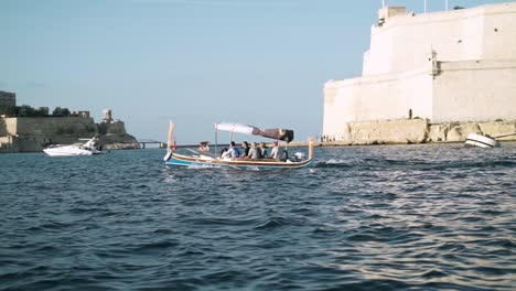 Tilt-up-from-sea-water-to-boats-sailing-in-the-harbour-of-Valletta,-Malta