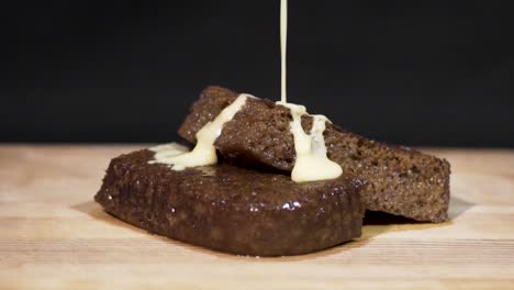 slow motion close up shot of custard being poured onto steaming hot malva pudding