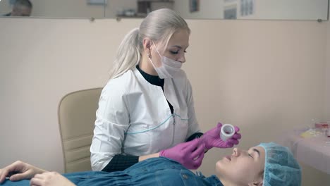 el maestro cubre las cejas de la chica pintadas con papel de aluminio en la clínica
