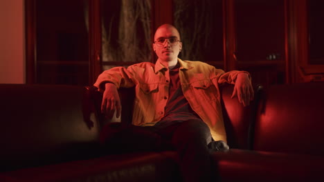 man sitting on sofa in red light