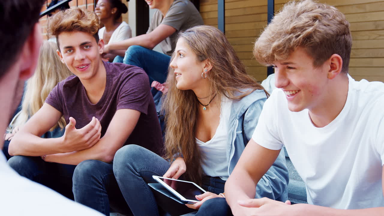 Jugendliche Schüler sprechen mit Lehrer vor Schulgebäuden