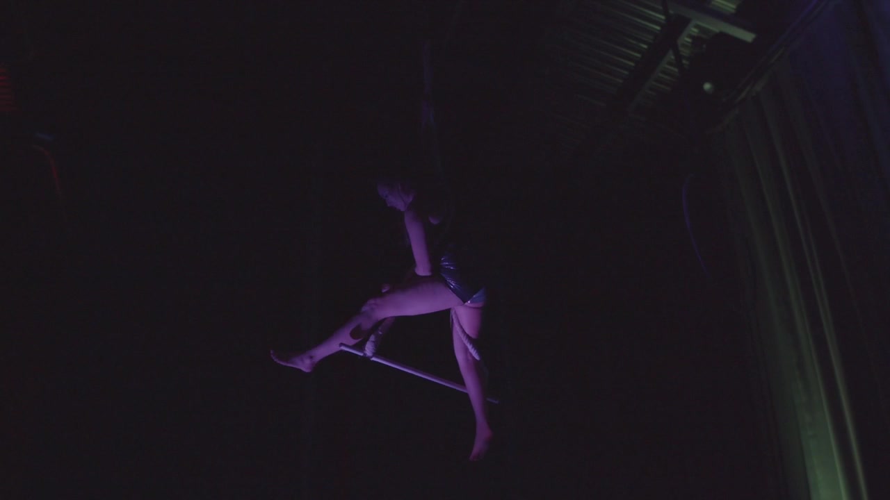 Acrobata che esegue danza aerea sul trapezio. Girato in 4K