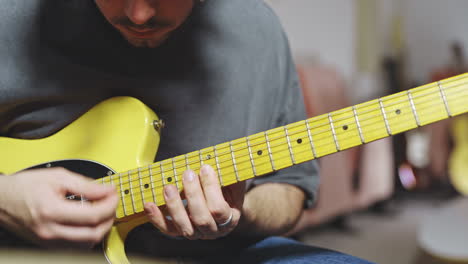 close up of skilled musician play stratocaster yellow guitar in studio