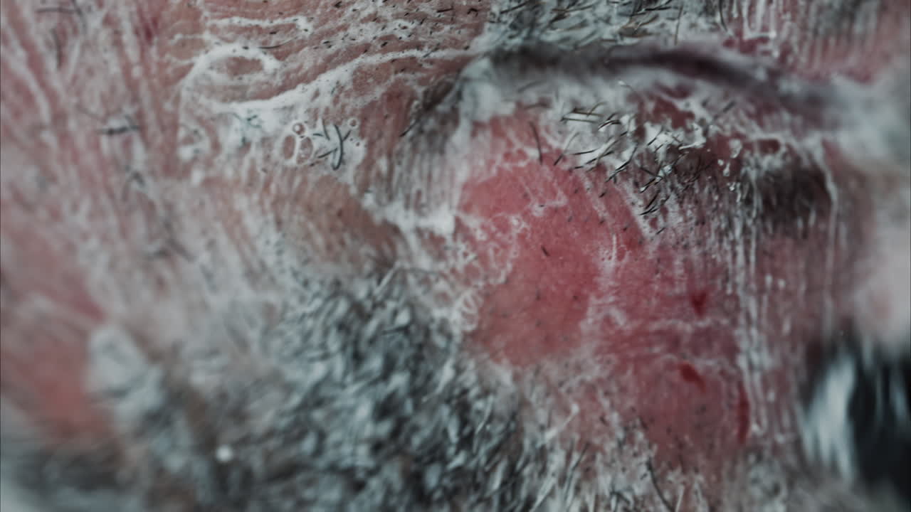 Close up of a man shaving his beard with a razor