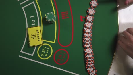 A high angle shot of a man plays at the casino and drawing the poker chips at the card table.