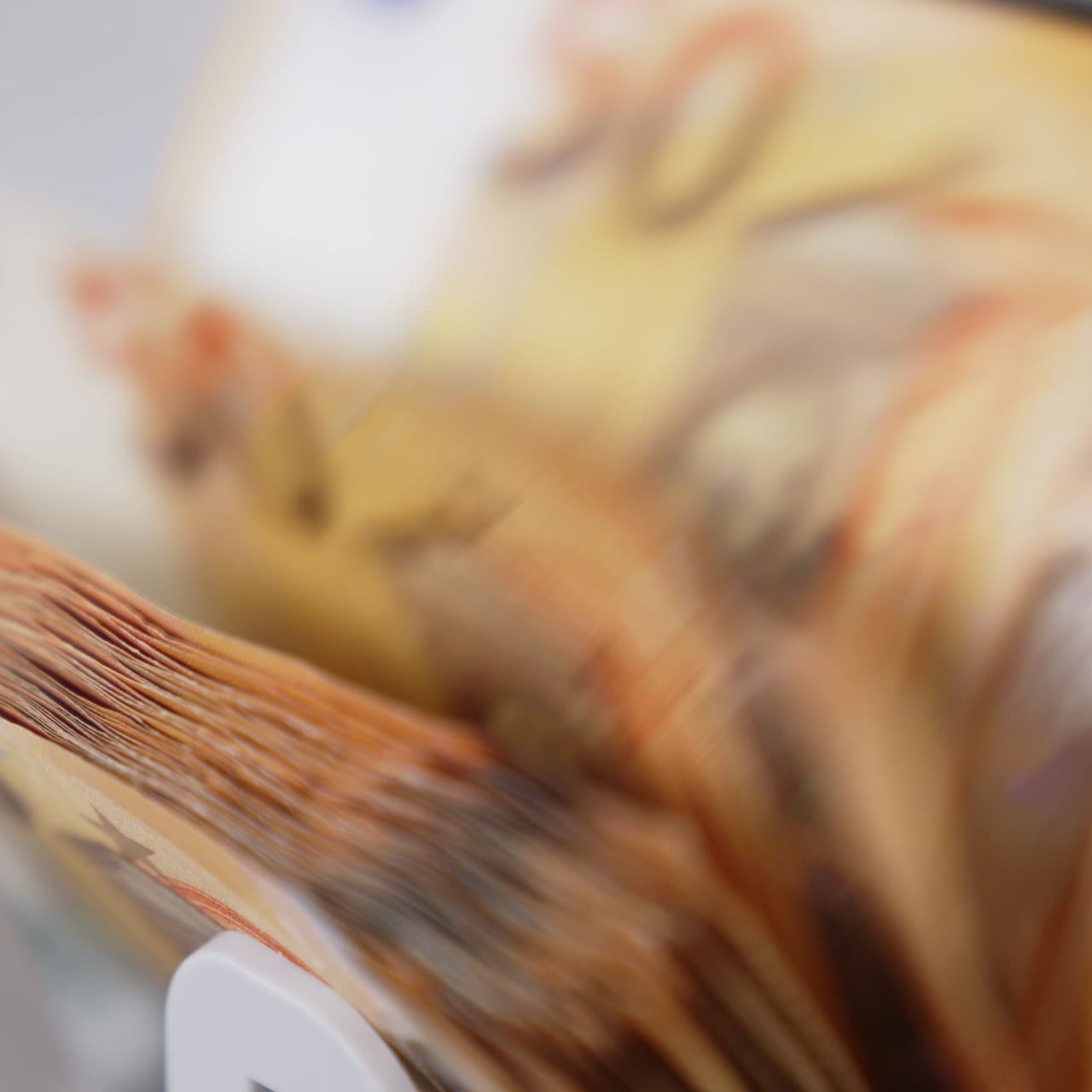 Rotating mechanism working in the electronic cash machine. Orange banknotes of fifty euro bills are being counted in the machine. Close up. Blurred backdrop