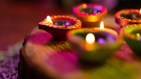 video of glowing lit diwali candles in circle on woven purple to green surface