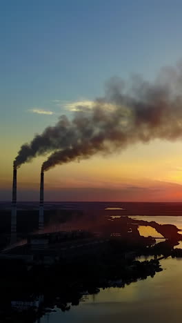 industrial building in country side. pipe with smoke near people which spend time near river vertical video