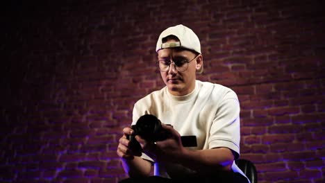 male hold digital camera in hands, red brick wall and purple hue backlight
