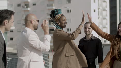 medium shot of happy colleagues giving high five to each other