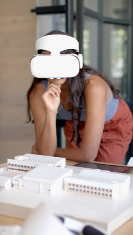 vertical video: using vr headset, woman analyzing architectural model in modern office