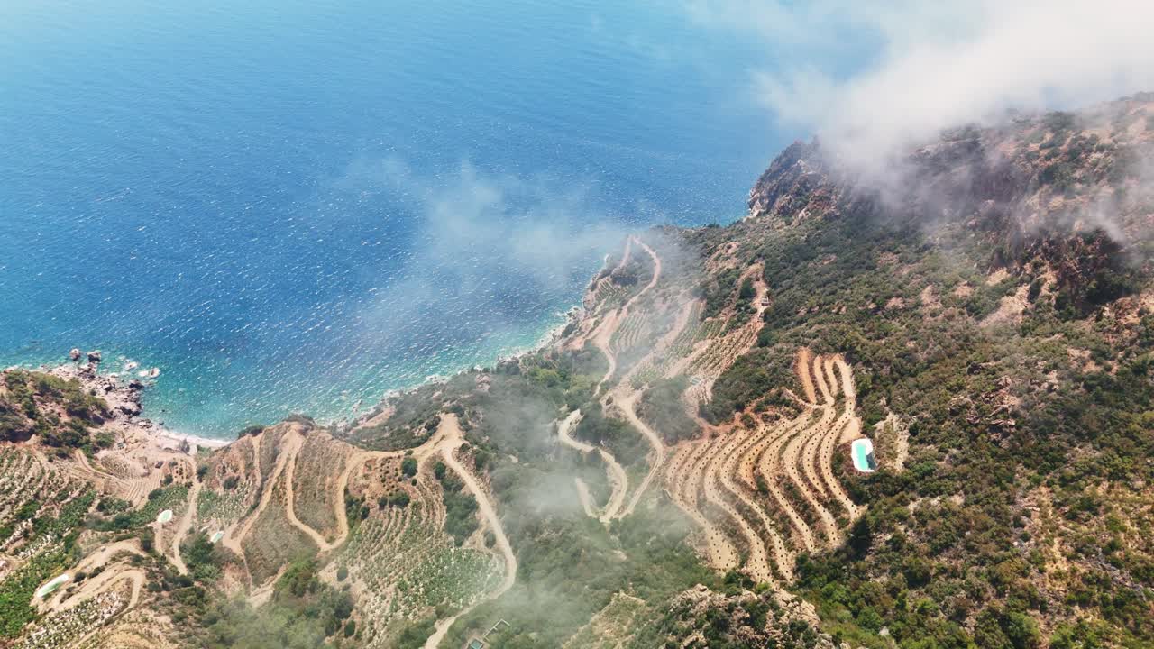 Aerial view of terraced hills by the sea under a bright sky
