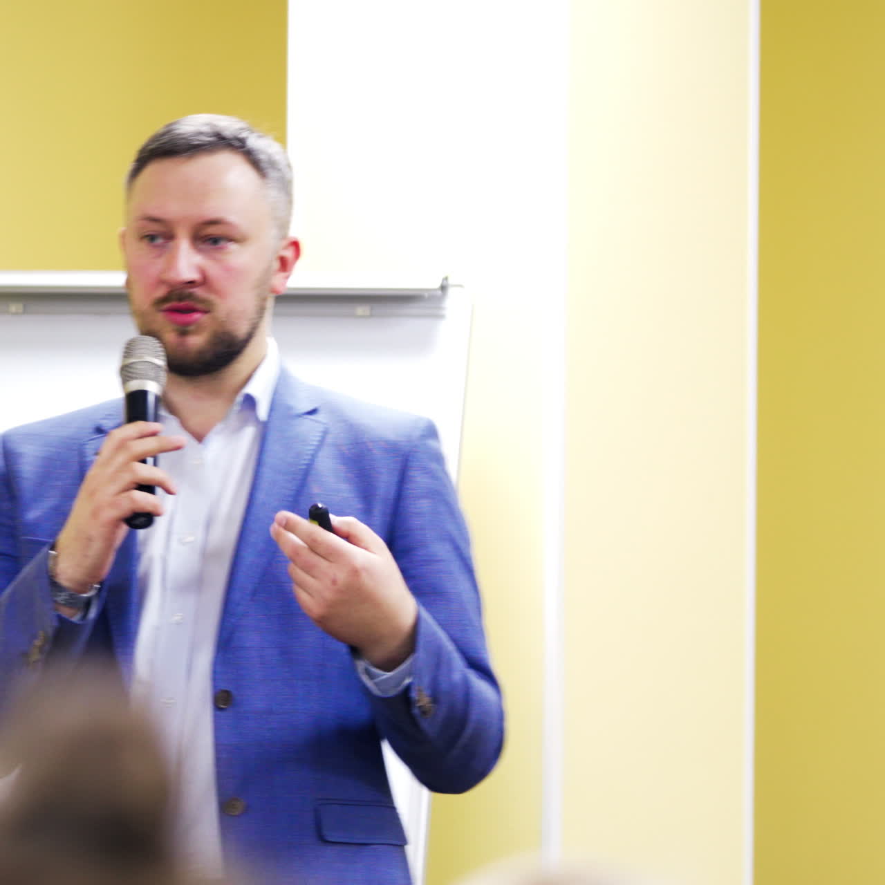 Speaker at business forum talking to the microphone giving advices. Businessman in suit at the conference hall. Business and Entrepreneurship