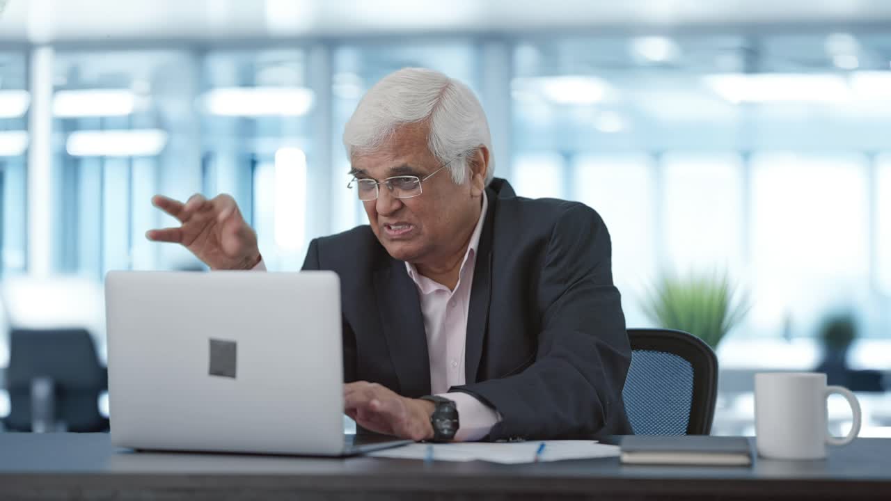 Dirigente indiano senior stressato che lavora al portatile
