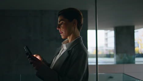mujer oscura usando teléfono inteligente en la terraza de la oficina. mujer de negocios centrada en el desplazamiento