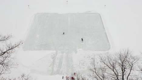 Aerial,-two-people-playing-ice-hockey-outdoors-on-an-ice-rink-made-on-frozen-lake