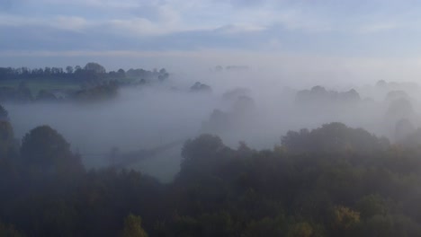 Aerial-shot-of-dense-Autumnal-woodland,-with-thick-fog-shot-at-Dering-woods,-Kent,-UK