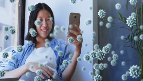 Animation-of-covid-19-cells-over-asian-pregnant-woman-using-smartphone