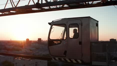 high above the city, a crane operator skillfully maneuvers their equipment as the sun sets, providing a breathtaking view of the urban landscape and shimmering skyline.